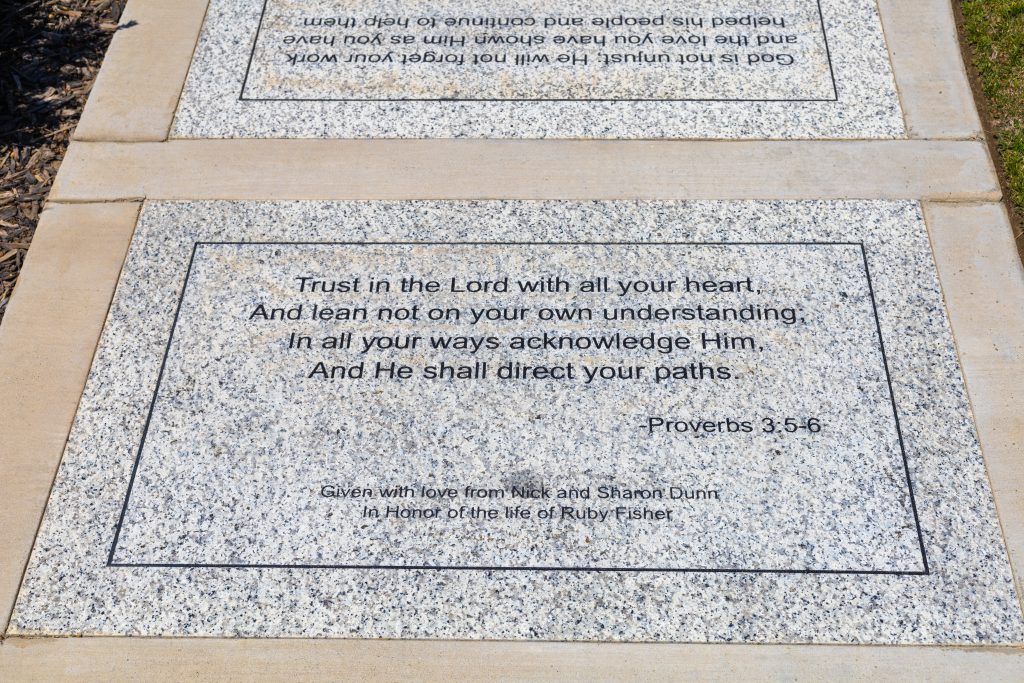 A granite plaque inscribed with Proverbs 3:5-6, which reads: 'Trust in the Lord with all your heart, and lean not on your own understanding. In all your ways acknowledge Him, and He shall direct your paths.' The plaque is dedicated with love from Nick and Sharon Dunn in honor of the life of Ruby Fisher.